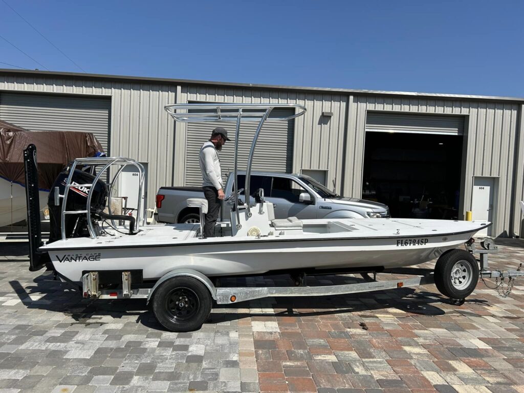 a white speed boat on a trailer with a man standing on the deck, looking at the steering wheel