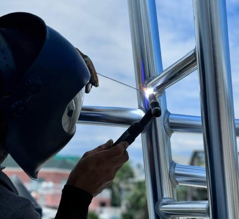 a welder wearing mask and using a torch to seal a joint